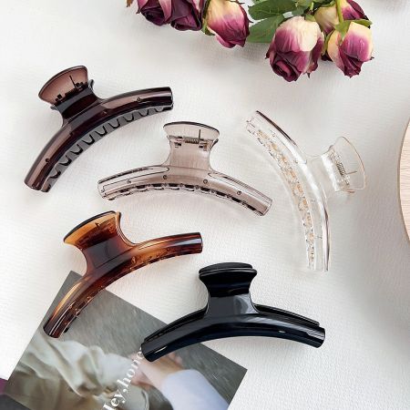 A collection of arc-shaped hair clips in various colors, including brown, black, and translucent.