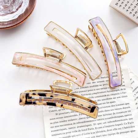 Women Acetate Hair Claws with Gold Metal Finish - A collection of women's acetate hair claws in various colors like pink, purple, white, and tortoiseshell, all featuring a stylish gold metal finish.
