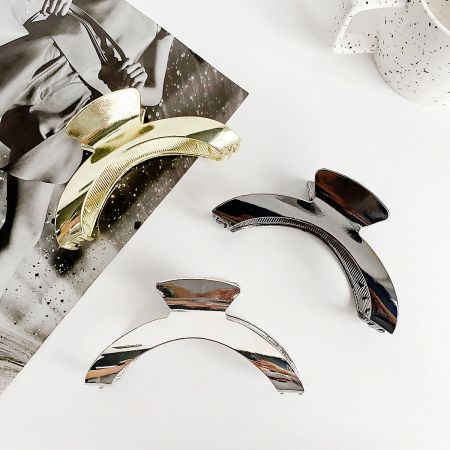 Three stylish metal hair clips in gold, silver, and a dark finish, arranged for wholesale display.