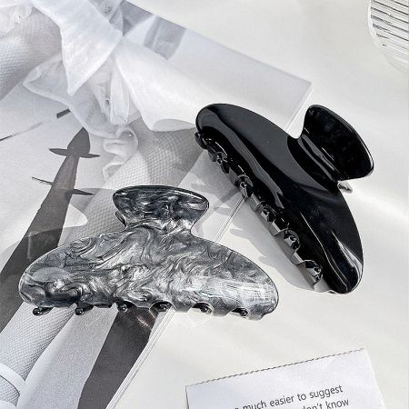 A classic black and a textured silver claw hair clip side by side.