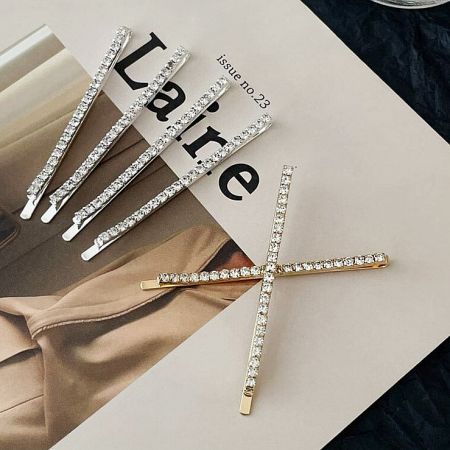 Four sparkling rhinestone hair clips stylishly placed on a magazine page, showcasing their versatility.