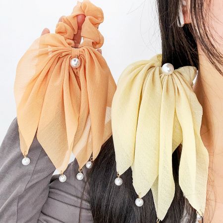 Two stylish hair scrunchies with elegant bow designs and pearl details.