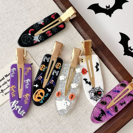 A pair of Halloween-themed 'Bride' hair clips, one purple and one white, with spooky designs.