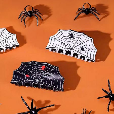 A white acrylic hair claw with a detailed spider web pattern.