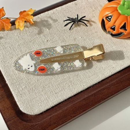 A white glitter hair clip featuring a cute ghost design for Halloween.