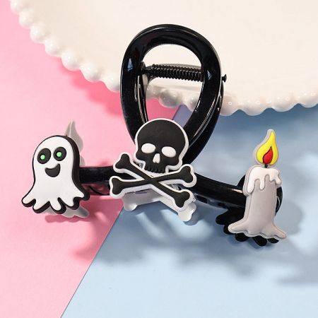 Close-up of a Halloween claw clip featuring ghost, skull, and candle cartoon figures.