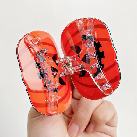 Halloween Ghost and Pumpkin Hair Clip Set - A set of two festive Halloween hair clips, one shaped like a smiling jack-o'-lantern and the other like a friendly white ghost, made from plastic.