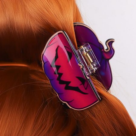 Close-up of a jack-o'-lantern Halloween hair clip worn in red hair.