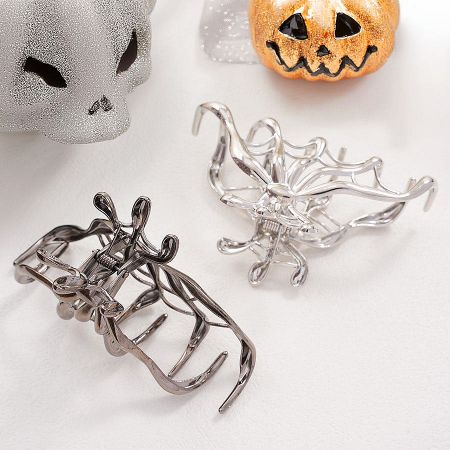 A detailed view of two metal hair clips with an intricate spider web design, perfect for Halloween.