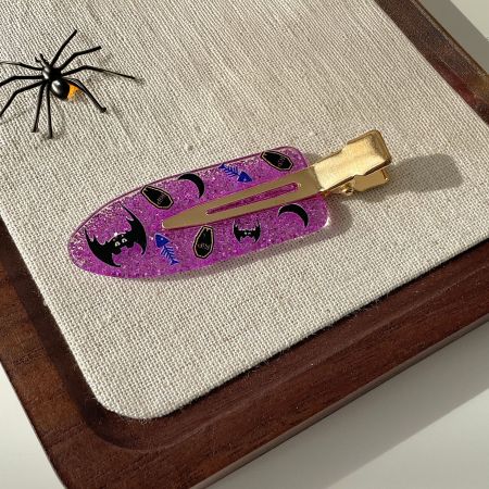 A single purple glitter hair clip with a Halloween theme, shown from the side.
