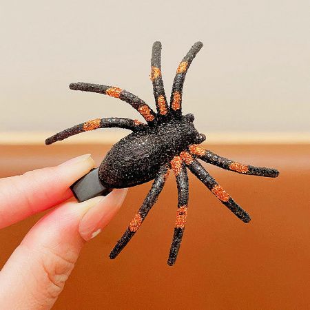 A black and orange striped spider hair accessory for Halloween costumes.