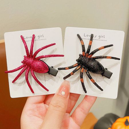 Two spider-themed hair clips, one red and one orange-striped, on display cards.