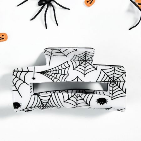 A close-up of a black spiderweb-patterned hair claw, ideal for Halloween hairstyles.