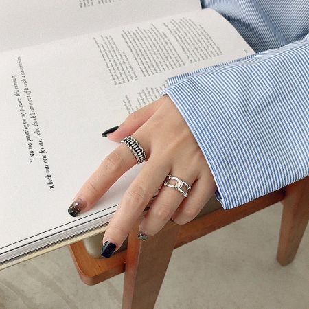 Close-up of a model's hand wearing the vintage-style sterling silver ring set, showcasing the assorted textures.