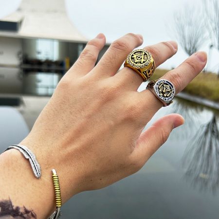 A collection of custom men's jewelry, including the Masonic ring, worn on a hand to showcase its style.