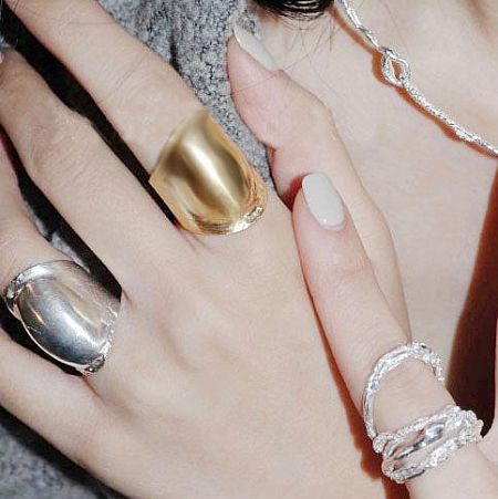 A model's hand showcasing the vintage brass rings in both gold and silver.