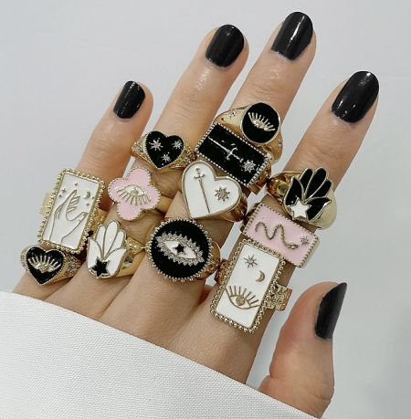A model's hand adorned with multiple Tarot Card Enamel Rings, demonstrating how they can be styled together.