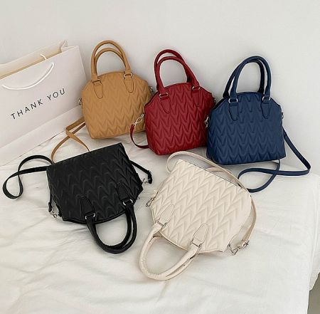 A collection of the crossbody bag available in five different colors, including tan, black, white, and grey.