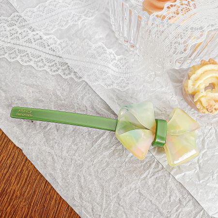 A vibrant green handmade acetate bow hair clip with 'FRANCE Handmade' inscription.