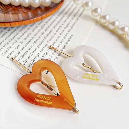 An orange and a white handmade heart-shaped hair clip from France.