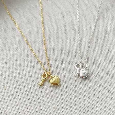 A close-up of the gold and silver heart and key pendants, highlighting the intricate details.