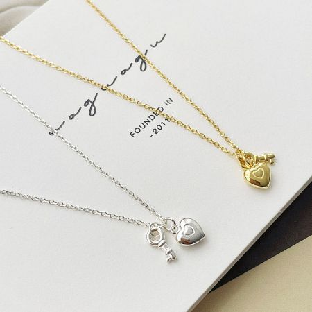 Gold and silver heart key necklaces displayed on a branded card for wholesale.