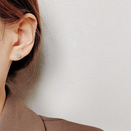 Detailed view of the heart-shaped stud earring featuring a light blue opal glass stone.