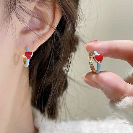 Close-up view of the gold and enamel heart huggie earring being worn.