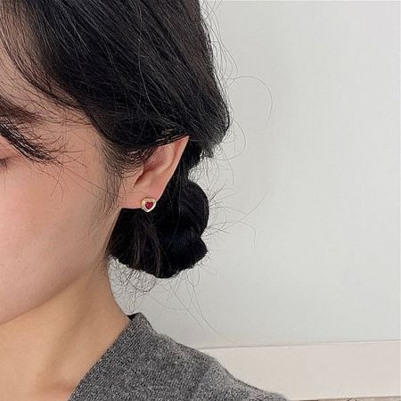 Detailed close-up shot of a woman wearing the sterling silver heart-shaped earrings.