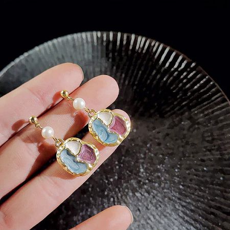 Charming heart-shaped earrings with a colorful puzzle design in gold, accented with pearls.