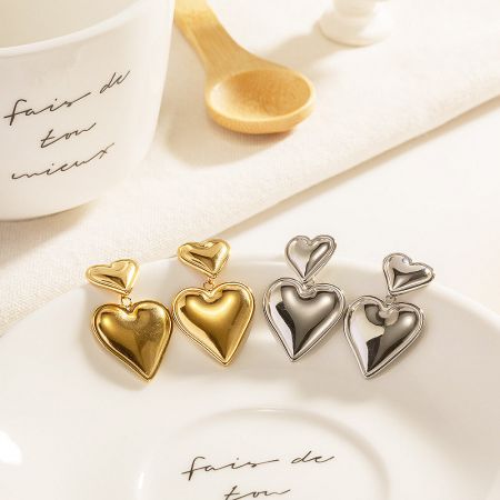 A close-up of the gold and silver double heart earrings on a decorative plate.