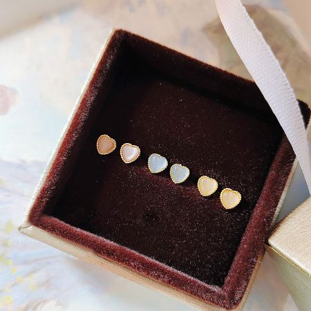 A set of mini heart stud earrings elegantly presented in a jewelry box.