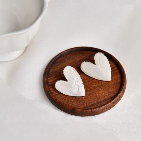 The vintage heart-shaped stud earrings arranged on a rustic wooden coaster.
