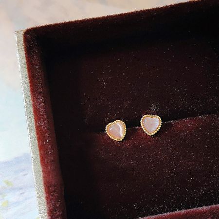 Close-up of the gold-plated heart stud earring with a pink opal glass stone.