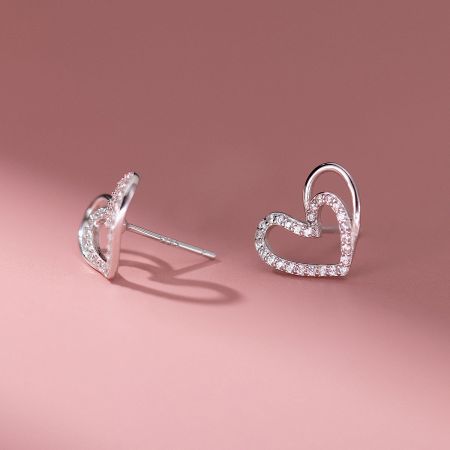 Detailed view of the silver hollow-out heart stud earrings with diamond details.