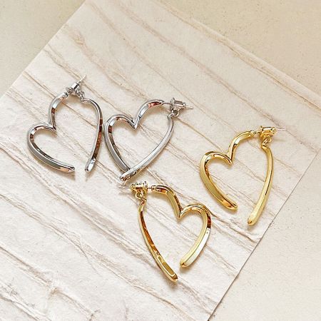 Top-down view of the geometric heart drop earrings in both silver and gold finishes.