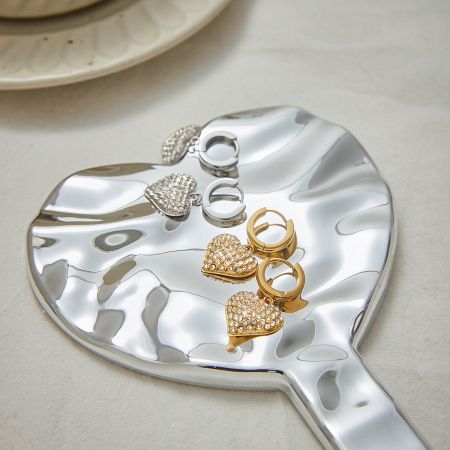 Gold and silver Heart Zircon Hoop Earrings elegantly arranged on a decorative tray, emphasizing their high-quality finish.