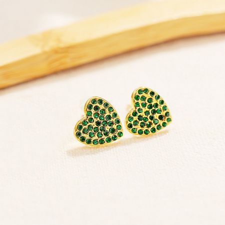 Detailed shot of the heart-shaped earrings, highlighting the intricate pave setting of the green gemstones.