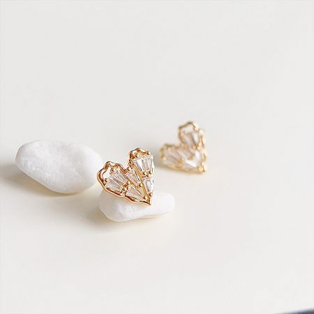 A pair of heart-shaped gold earrings with clear zircon stones.