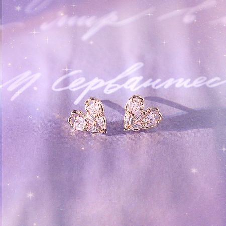 Promotional image of the heart-shaped gold earrings with clear gemstones.