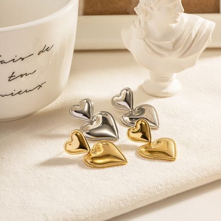 Stainless Steel Double Heart Statement Drop Earrings (5 pairs) - A stylish display of stainless steel double heart statement drop earrings in both gold and silver, presented with elegant decorative props.