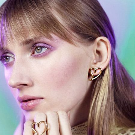 Lifestyle image of a model wearing the heart-shaped earrings, showing their versatility and style.