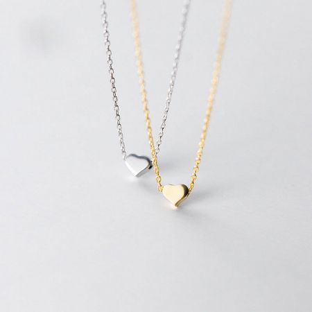 Close-up of the gold and silver tiny heart necklaces showcasing their delicate design.