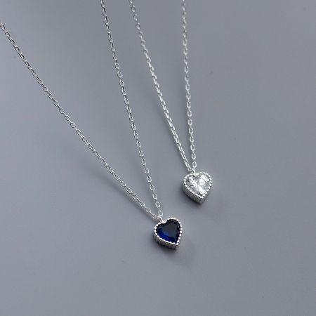 Two heart necklaces shown side-by-side, one with blue and one with clear gemstones.