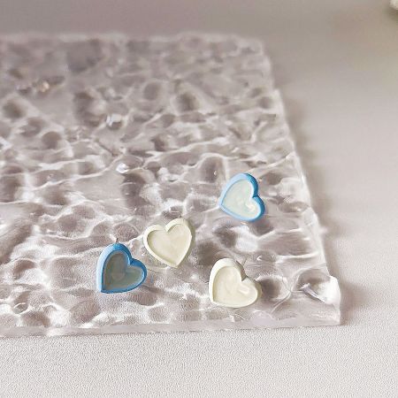 An artistic display of white and blue enamel heart-shaped stud earrings.