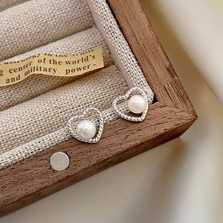 A pair of 925 sterling silver hollow heart pearl stud earrings with intricate braided frames.