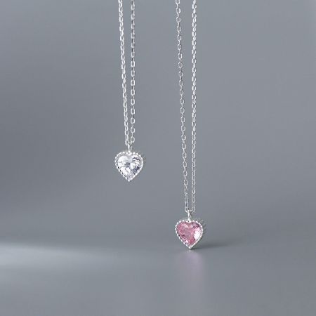 Close-up of two sterling silver heart necklaces with sparkling gemstones.