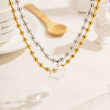 Stainless Steel Chunky Ball Chain Heart Pendant Necklace - A pair of stainless steel chunky ball chain necklaces, one in gold and one in silver, each featuring a transparent quartz glass heart pendant.