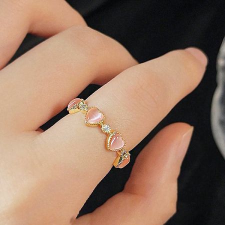 The pink opal heart ring worn on a finger to showcase its fit and style.