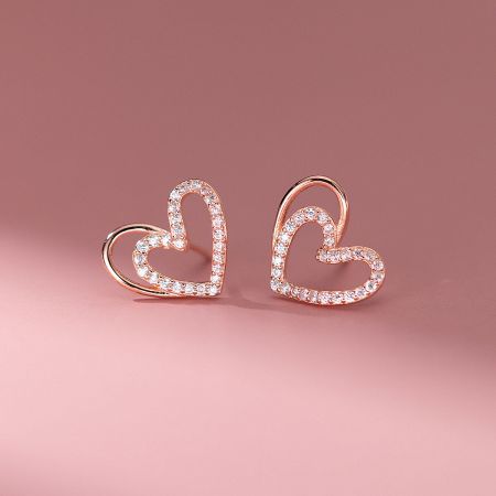 Detailed view of the rose gold double heart stud earrings with white gemstone accents.